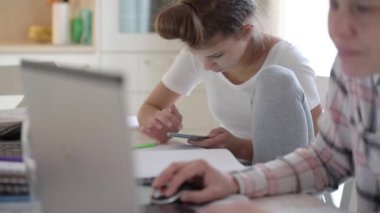 Genç kız, karantina sırasında ailesiyle birlikte evden ders çalışırken akıllı telefondan sosyal medyaya kayıyor.