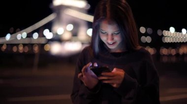 Gece sokakta akıllı telefon kullanan genç bir kızın görüntüleri.