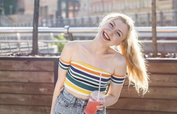 güzel genç gülümsemek kız bir semt güneşli bir günde cadde üzerinde serinletici meyve kokteyli kısa etekli buzlu içecekler