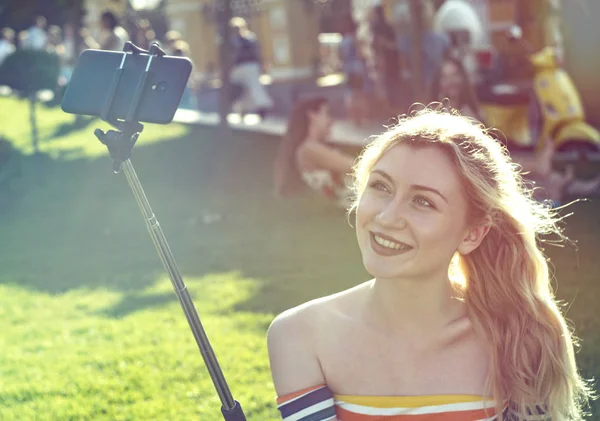 bir akıllı telefonda selfie yapıyor güneşli bir gün bir şehir parkında güzel genç sarışın kız