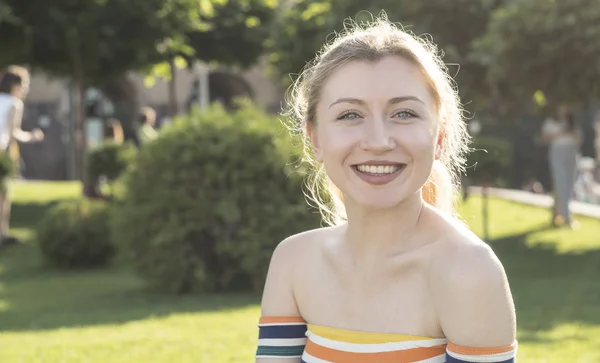 Güzel gülümseme genç sarışın kız bir şehir parkı, central park güneşli bir portresi