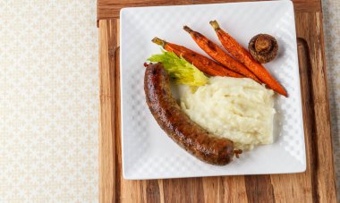 Ahşap arka plan üzerinde patates püresi kare plaka ile ızgara sosis