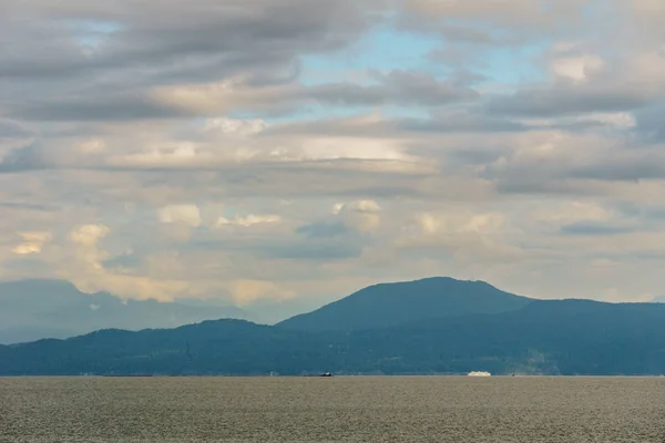 Vista sull'oceano verso le montagne con cielo nuvoloso — Foto Stock