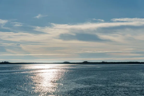 Blauwe skyline met zon en wolken boven het water van de Oceaan op zomertijd. — Stockfoto