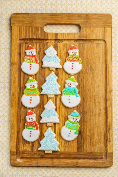 Navidad muñeco de nieve y galletas de árbol en la tabla de cortar fondo de selebración de invierno . — Foto de Stock