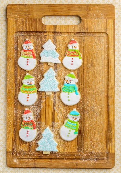 Navidad muñeco de nieve y galletas de árbol en la tabla de cortar fondo de selebración de invierno . — Foto de Stock