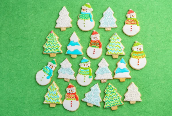 Muñeco de nieve de Navidad y galletas de árbol sobre fondo verde . — Foto de Stock