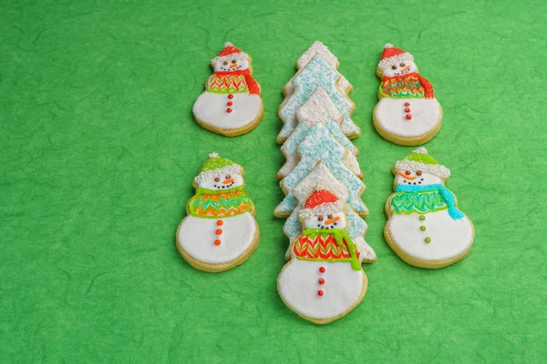 Muñeco de nieve de Navidad y galletas de árbol sobre fondo verde . — Foto de Stock