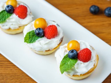 Çilek ve krema bir plaka üzerinde Mini cheesecakes.