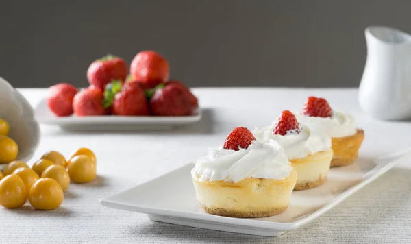 Çilek ve krema bir plaka üzerinde Mini cheesecakes.