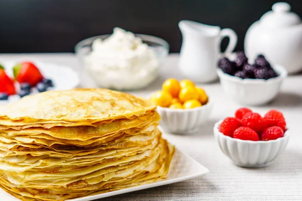 Pile of just made hot Russian pancakes or blini with berries.
