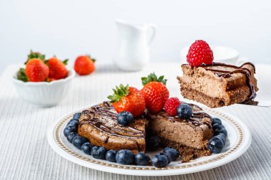 Yaban mersini çilek yuvarlak tabağa ahududu ile büyük çikolata cheesecake.