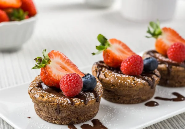 Delicious chocolate mini cheesecakes with blueberry strawberry raspberry. — Stock Photo, Image