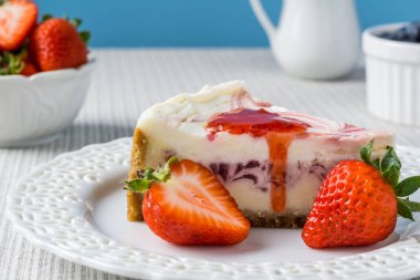 Çilek mavi duvara bir tablo ile lezzetli peynirli kek.