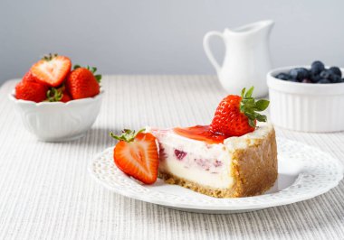 Çilek beyaz duvara bir tablo ile lezzetli peynirli kek.