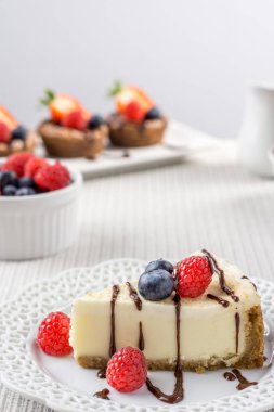 Çilek beyaz duvara bir tablo ile lezzetli peynirli kek.