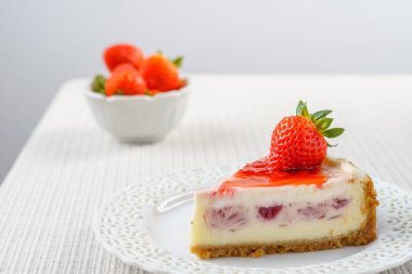 Çilek beyaz duvara bir tablo ile lezzetli peynirli kek.