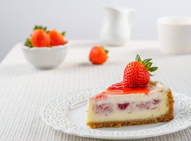 Çilek beyaz duvara bir tablo ile lezzetli peynirli kek.