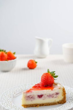 Çilek beyaz duvara bir tablo ile lezzetli peynirli kek.