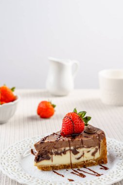 Çilek beyaz duvara bir tablo ile lezzetli çikolatalı cheesecake.