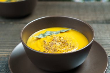 kahverengi seramik çorba tabağına kabak çorbası ile adaçayı yaprakları.