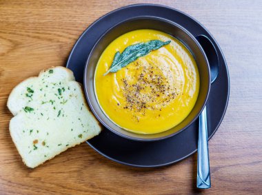 kahverengi seramik çorba plaka sarımsaklı ekmek ile adaçayı yaprakları ile balkabağı çorbası.