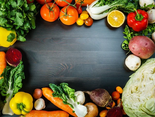 Rustik siyah arka plan ile sebze ve malzemeler çevre etrafında.