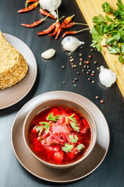 Kırmızı pancar çorbası çorba kahverengi kase üst görünümünde, siyah masa maydanoz ile.