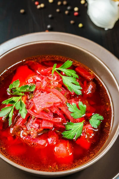 Sopa de borscht vermelho com salsa em tigela marrom vista superior, na mesa preta . — Fotografia de Stock