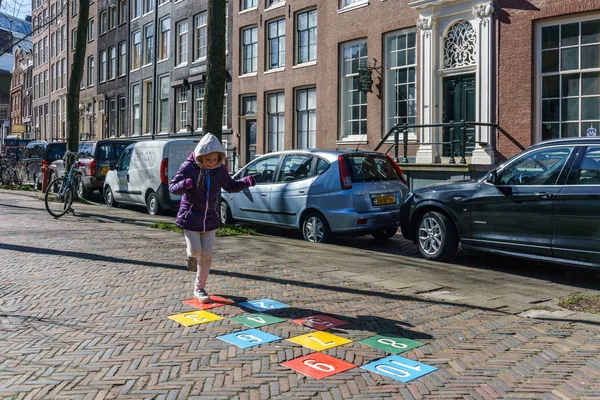 Amsterdam, Hollanda - 20 Mart 2018: Amsterdam sokakta oynarken küçük kız.