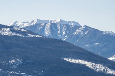 Güneşli bir bahar günü, ağaçlarla ve karla kaplı dağın en yakın manzarası.