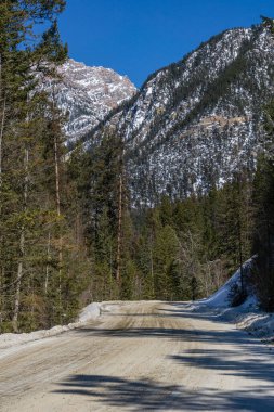 Dağlara giden boş, kirli bir yol ilkbaharın başlarında karla kaplı.