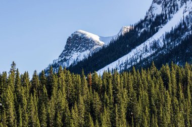 Karla kaplı yüksek kayalık dağlar. Mavi gökyüzü.