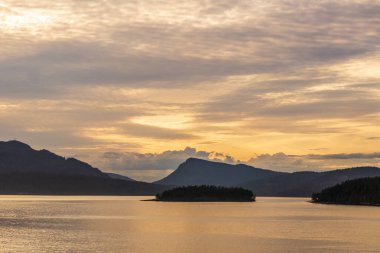 Turuncu gökyüzü dağları ve bulutlarıyla güzel günbatımı okyanus koyu