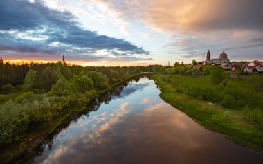 Bu fotoğrafta, çerçevenin büyük bir kısmı fırtınalı gökyüzü tarafından nehrin sakin suyuna yansıtılır. Sağda pembe bulutlar ve solda koyu mavi bulutlar. Sol tarafta yoğun bir orman yetişiyor. Gün batımı..
