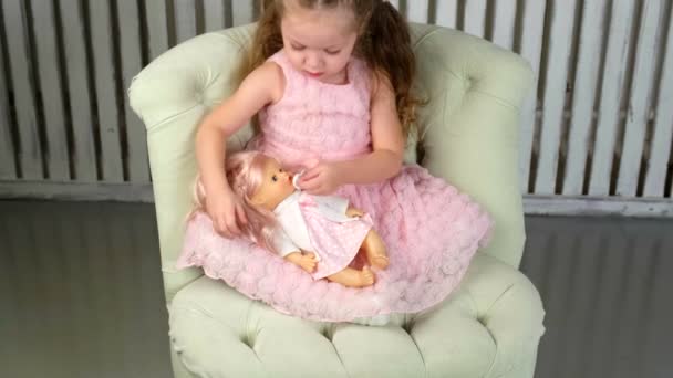Девушка, играющая в куклы, держит и обнимает — стоковое видео