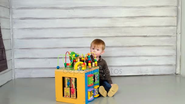 Netter kleiner Junge sitzt auf dem Boden und spielt — Stockvideo
