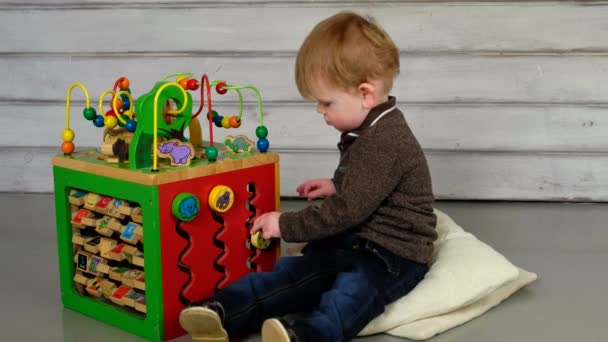 Netter kleiner Junge sitzt auf dem Boden und spielt — Stockvideo