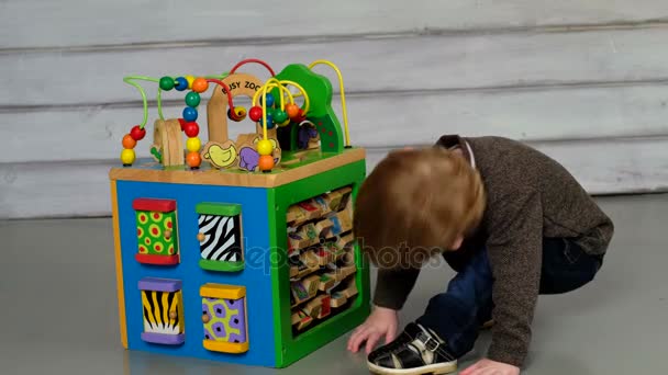 Söt liten pojke sitter på golvet och leker — Stockvideo