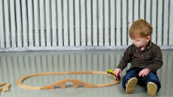 Kleine jongen spelen met houten spoorlijn — Stockvideo