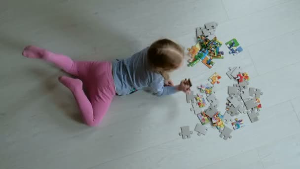 Niñas lindas jugando puzzles tumbados en el suelo — Vídeo de stock