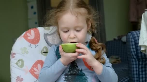 Щаслива дитина їсть зелене яблуко. Концепція здорового способу життя — стокове відео