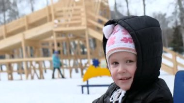 Kışın soğuk karlı gün sahada sallanan sevimli küçük kız