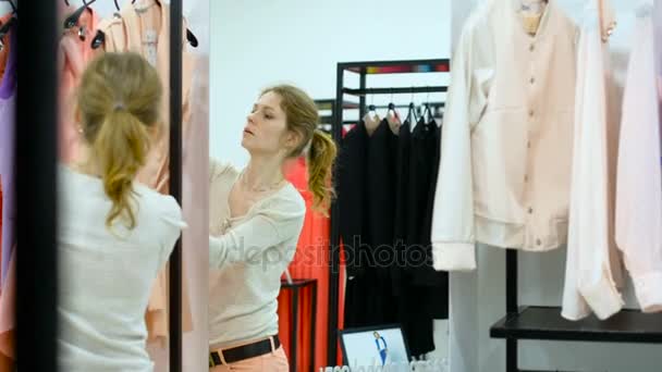 人和时尚，快乐的年轻女人微笑着，尝试在服装店的衣服的肖像 — 图库视频影像