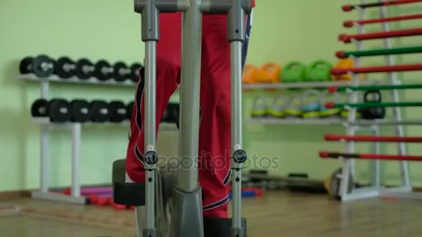 O femeie în vârstă pe un antrenor eliptic într-o sală de gimnastică 4k — Videoclip de stoc