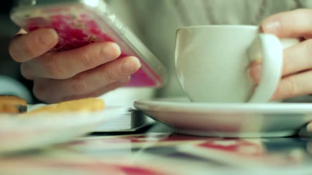 Una ragazza in un caffè beve cappuccino telefono 4k — Video Stock