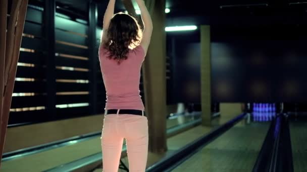 Молодая женщина бросает мяч в боулинг-клуб — стоковое видео
