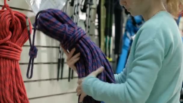 Wspinacz dziewczyna wybiera sprzęt w sklepie 4k — Wideo stockowe