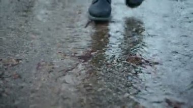 Bir su birikintisi bahar sıçramasına siyah çizmeler giyen kız
