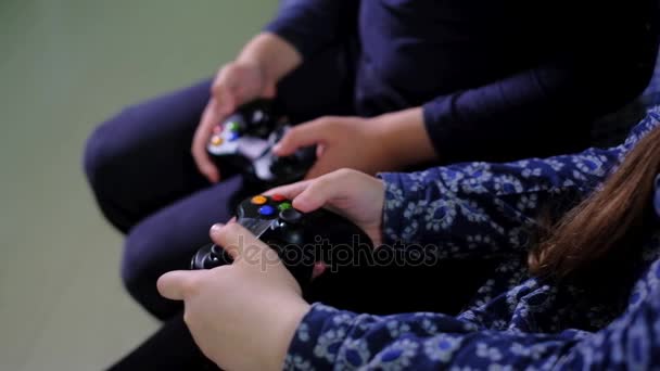 Menina bonita e menino estão jogando console de jogo e rindo enquanto sentado no sofá em casa bom — Vídeo de Stock